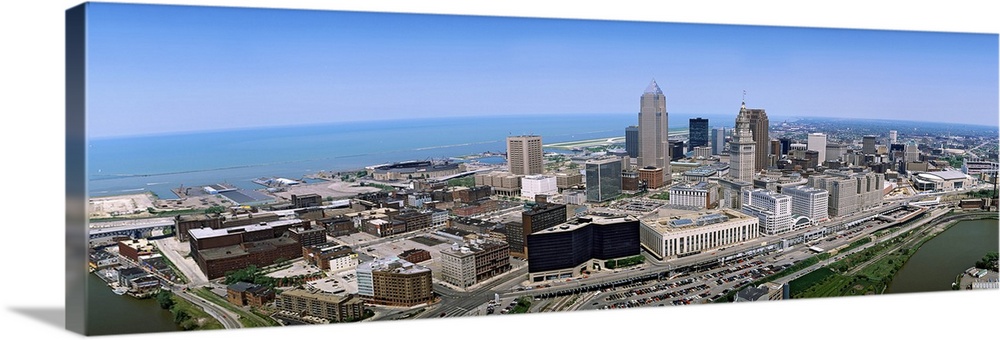 Horizontal, aerial photograph of the Cleveland Ohio skyline beneath a blue sky.