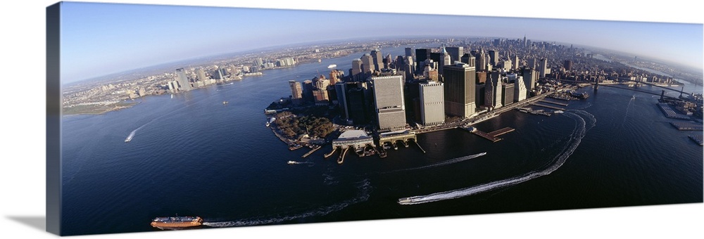 The Manhattan skyline is photographed from an aerial view showing the water that is surrounding it with boats driving arou...