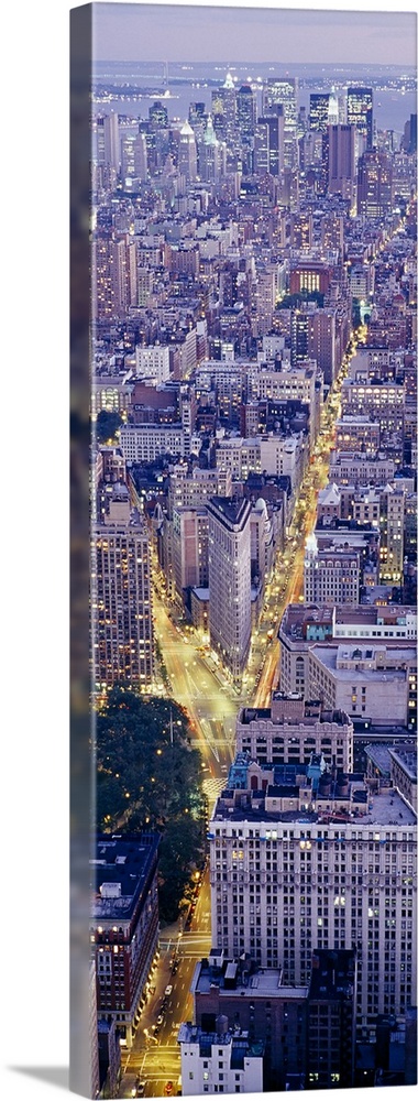 Tall panoramic piece of an aerial photograph taken of the skyline in Manhattan during dusk with the streets illuminated by...