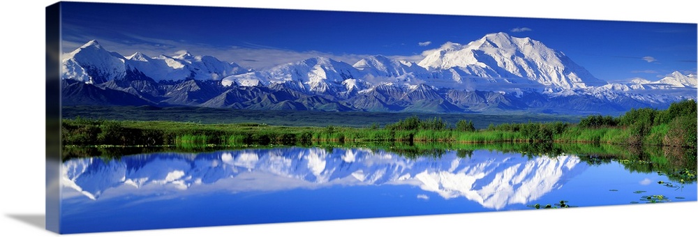 Panoramic view of snowcapped mountains and Mt. McKinley reflecting in still waters.