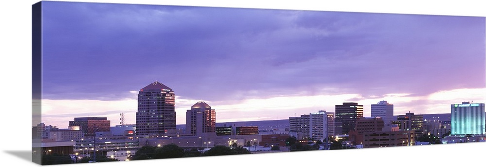 Panoramic photograph on a big canvas of the Albuquerque skyline with lit skyscrapers at night, beneath a cloudy sky in New...
