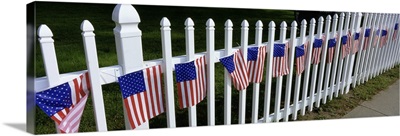 American flags hanging on a picket fence