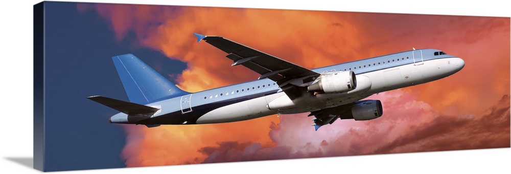 This large panoramic picture is of a commercial airplane ascending into warm toned clouds.