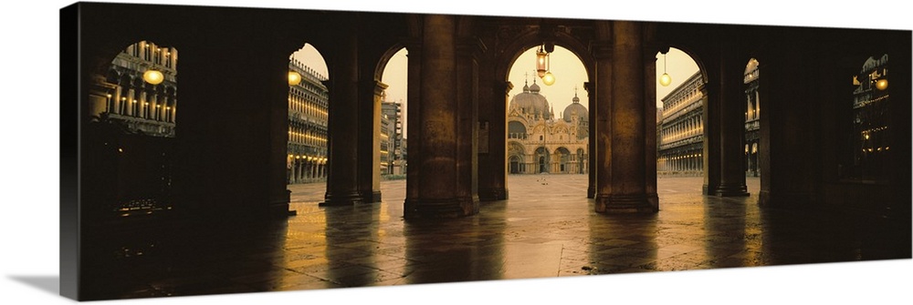 Panoramic photograph taken of St. Marks Square in Venice looking through stone arches and into the square.