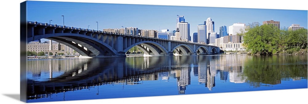 Big panoramic photo of a bridge spanning across a river in Minneanapolis, Minnesota (MN) on a sunny day.