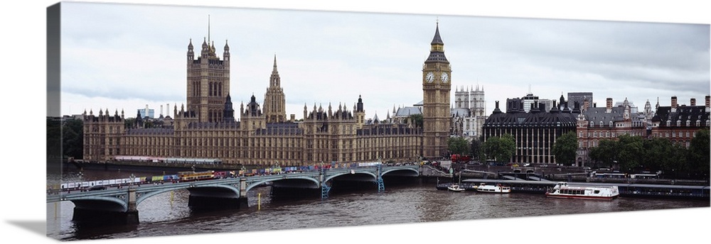Panoramic photo of a bridge leading into the city with boats in the river Thames, under a skyline of historic buildings.