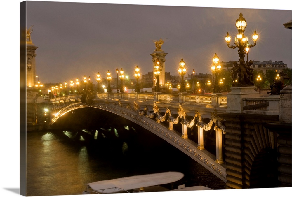 Big photo on canvas of a bridge lit up going over a river in France.