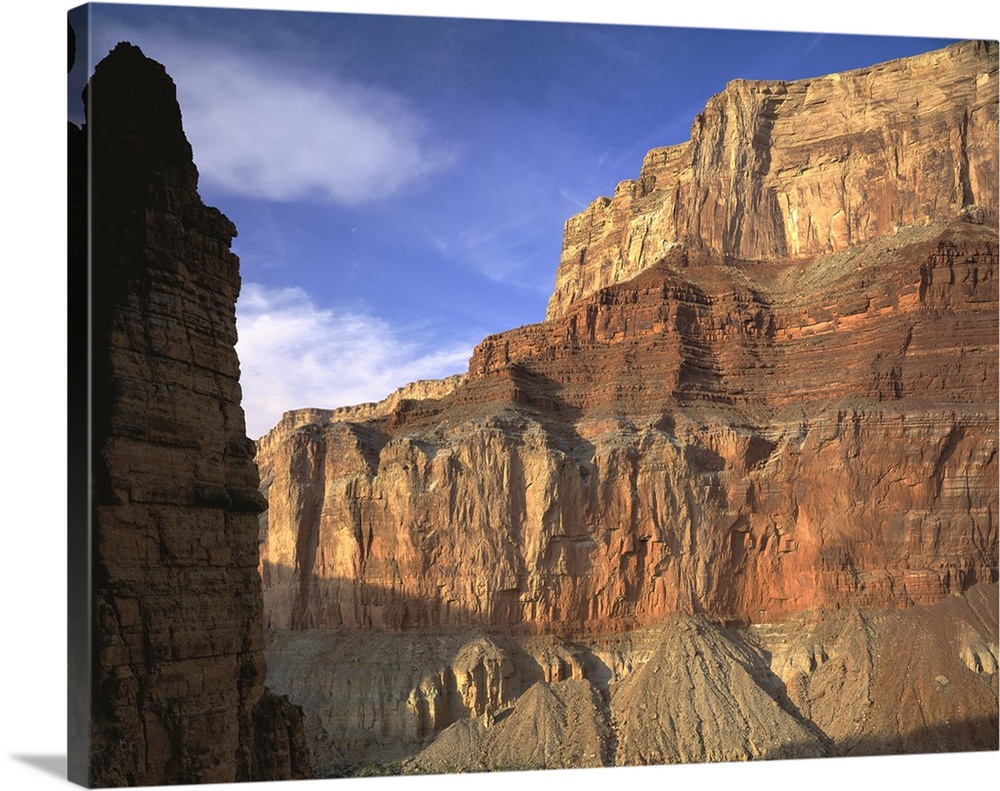 Large, close up photograph of the side of  a mountain beneath a blue sky in the Grand Canyon National Park, in Arizona.