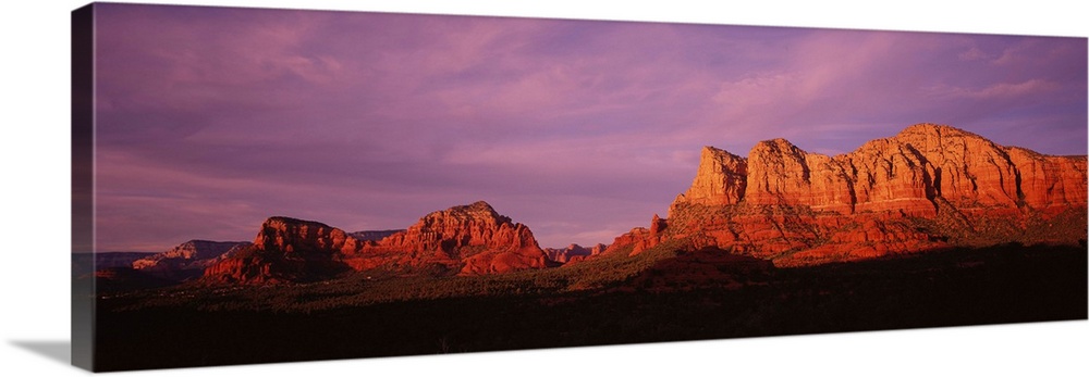 This photograph is a panoramic wall hanging that captures the fading light illuminating the desert cliffs.