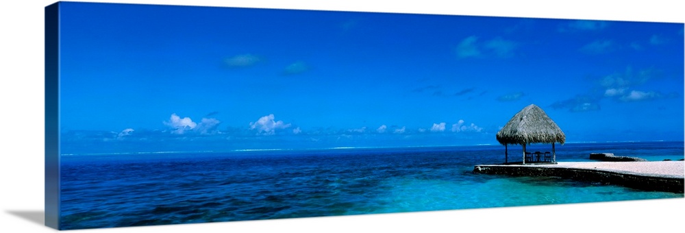 This large wall art is a sweeping panoramic photograph of the ocean horizon and a single shady shelter on the edge of the ...