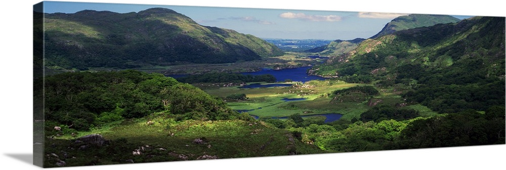 View of an Irish valley with a stream running through the lush green landscape between the rolling hills.
