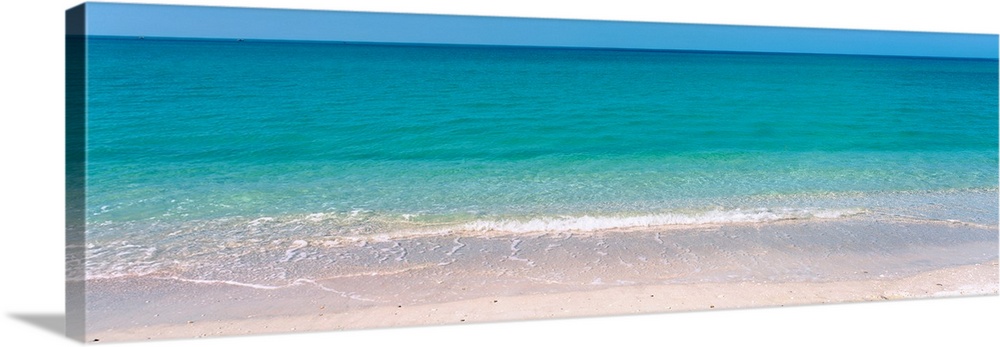 A panoramic photograph of a calm sea of tropical colored water.