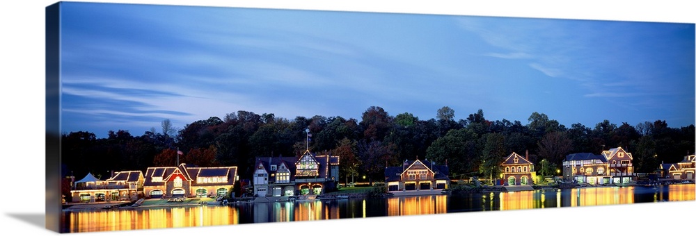Panoramic photograph taken of Boathouse Row in Philadelphia at night with a backdrop full of trees.  The bright lights of ...