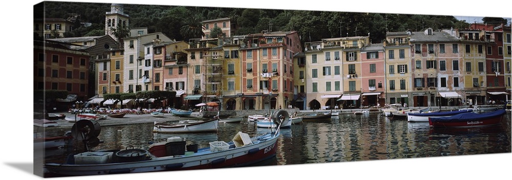 Panoramic photograph on a big canvas of a many boats anchored in the Italian Riviera harbor, a line of tall, colorful buil...