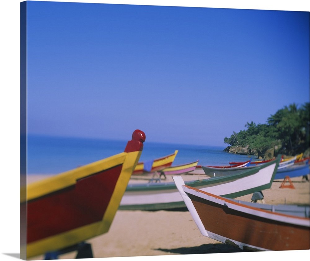 Big canvas photo of colorful wooden boats sitting on a beach with an ocean in the background.