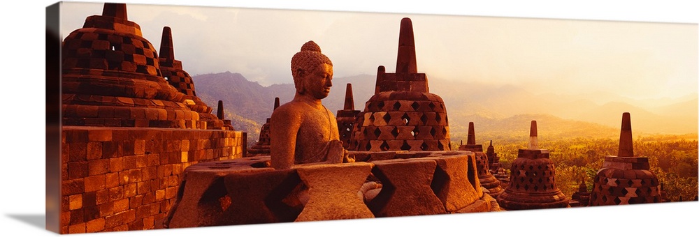 Panoramic photograph of the top of Borobudur Buddhist Temple overlooking Java, Indonesia during a golden sunset.