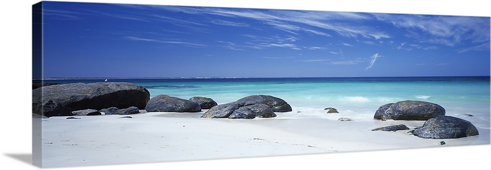 Wide angle photograph on a large canvas of big rocks on a white sand beach near the crystal blue waters of Flinders Bay in...
