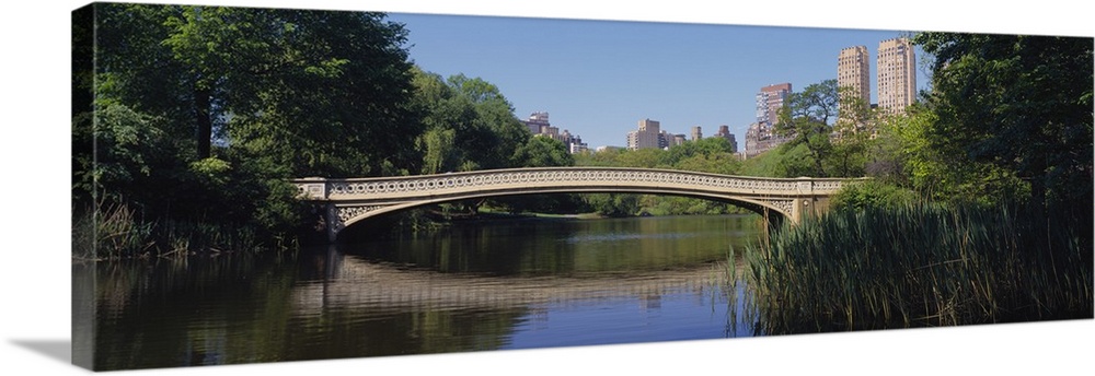 Panoramic view of a footbridge crossing a lake in New York City's Central Park