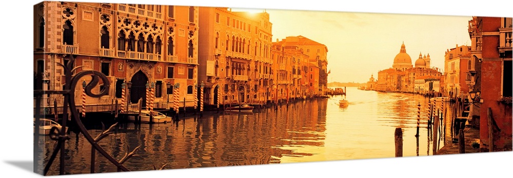 This panoramic photograph captures a still moment in the canals at sunset and this historic city as single gondola approac...