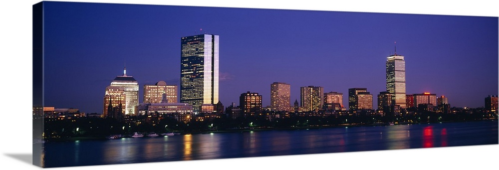Large panoramic photograph of skyscrapers and other buildings lit up lining the Charles River in Boston, Massachusettes at...