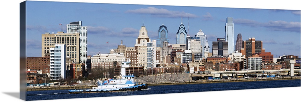 Giant panoramic photo of the city of Philadelphia, Pennsylvania (PA). A large barge chugs along the Delaware River as skys...