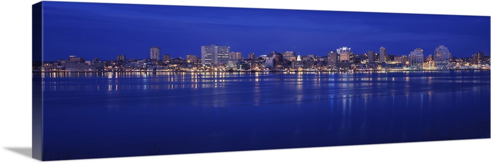 Large panoramic print of buildings lit up along a water front at night in Canada.