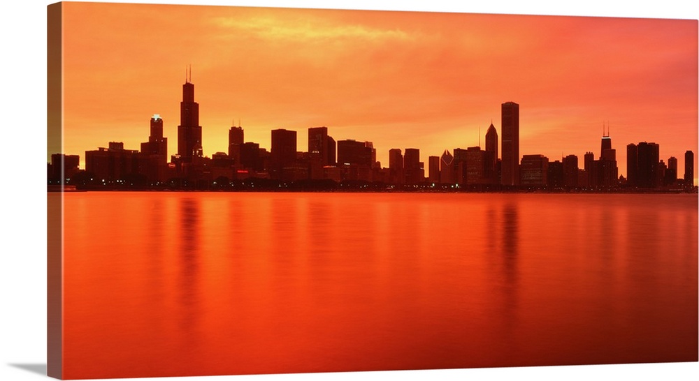 Large panoramic photograph of the Chicago, Illinois (IL) waterfront at dusk with the sun's rays reflecting off Lake Michigan.