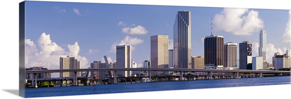 This urban landscape wall art is the city skyline taken from the water with a roadway passing in front of the skyscrapers.