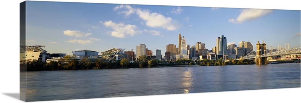 Wide angle photograph on a large wall hanging of a distant Cincinnati skyline along the edge of the Ohio River, beneath a ...