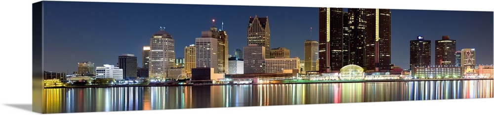 Panoramic photograph of skyline after sunset with city lights reflected in waterfront.