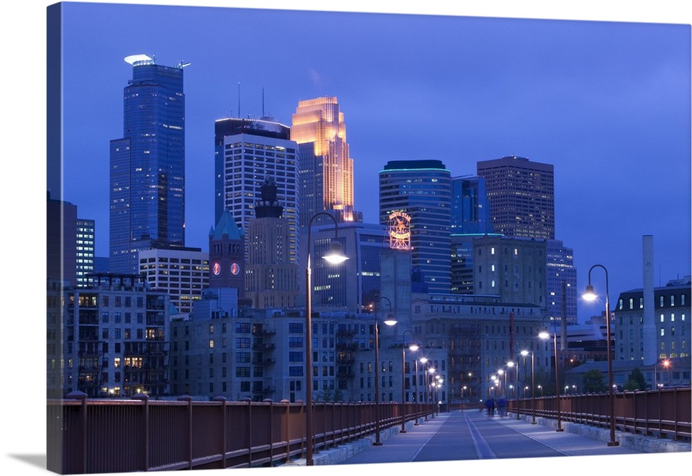Giant photograph taken of skyscrapers filling the Minneapolis skyline at night.  The light posts in the foreground can be ...