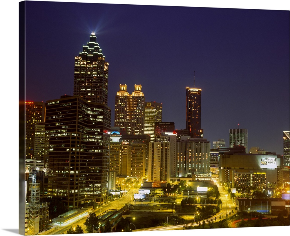 Large photograph displays a busy capital city in the Southeastern United States as the lights of tall buildings and skyscr...