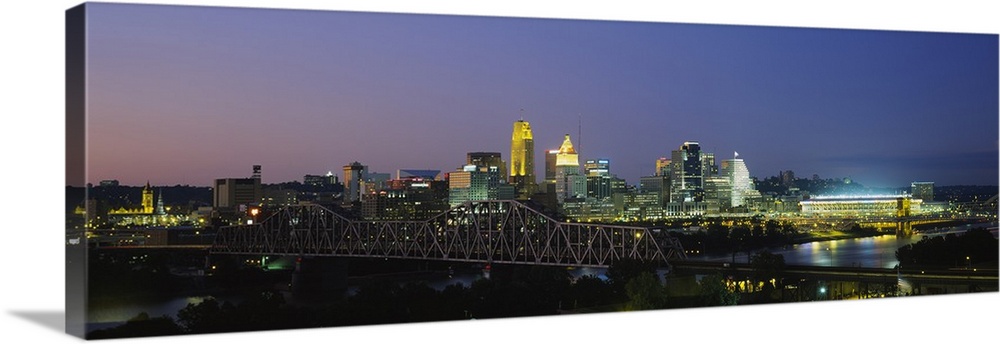 The Cincinnati skyline is photographed in panoramic view and illuminated under a night sky.
