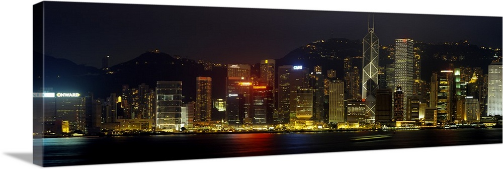 Panoramic photograph of the Hong Kong skyline, lit up at night, reflecting in the water, in China.