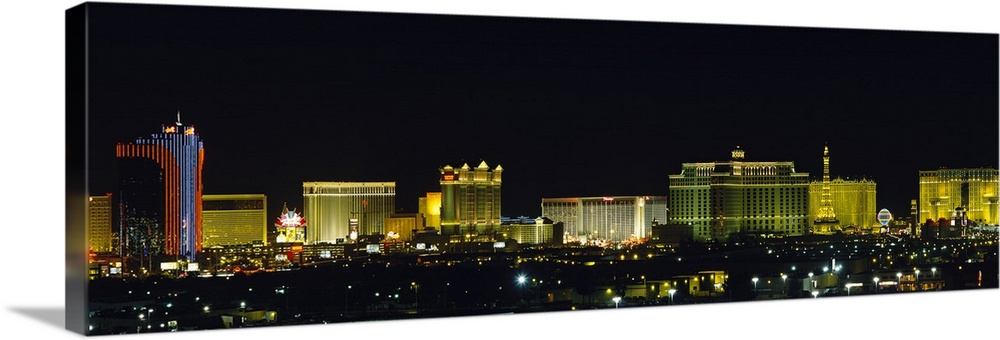 Landscape photograph on an oversized wall hanging of the brightly lit buildings of the Las Vegas skyline at night, a pitch...