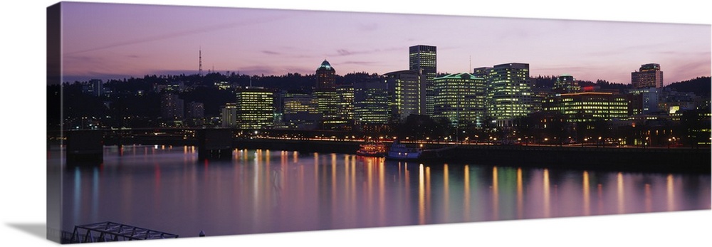 This is a cityscape glowing in the evening light and reflecting in the surface of the water in this panoramic wall art.