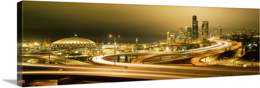 Wide angle, giant panoramic photograph of curving highways leading to a brightly lit skyline in Seattle, Washington.