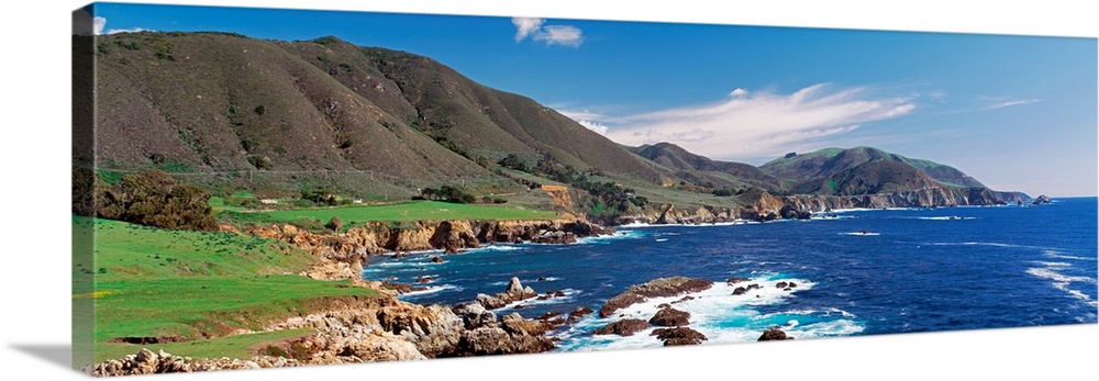 Wide angle photograph of the coastline in Big Sure, California.  Hills jutting into the blue waters of the Pacific Ocean.