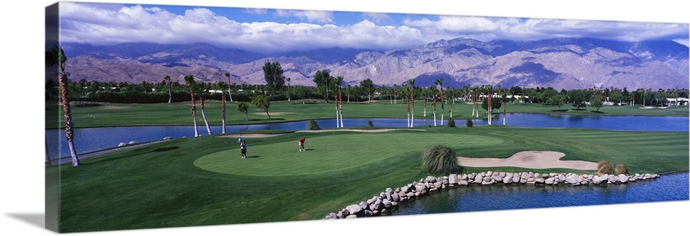 This panoramic photograph shows the immaculate oasis with mountains and clouds in the distance.