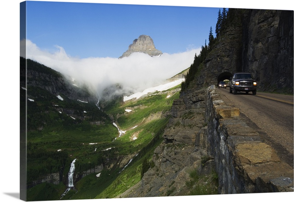 Cars on Going to the Sun Road through mountainside tunnel, low clouds in valley, Glacier National Park, Montana