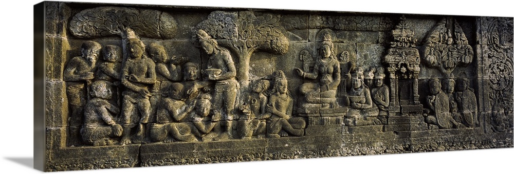 This elongated piece is of a stone wall that has had artwork carved into it.
