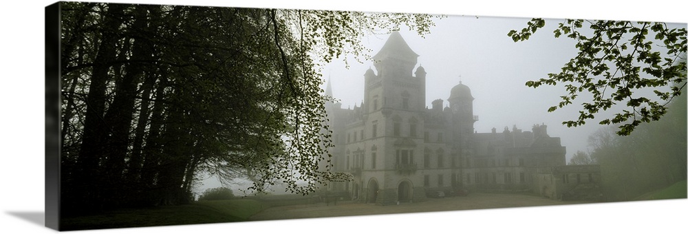 A large castle is faintly shown behind fog and surrounded by trees.