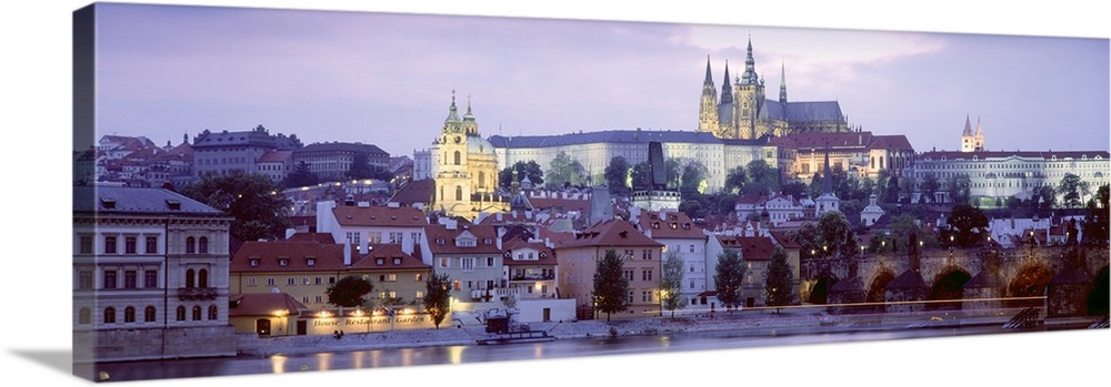 Wide angle photograph of buildings in Prague, Czech Republic, lit up at night, including Hradcany Castle.