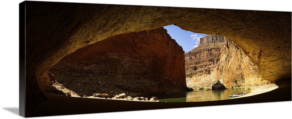 Wide angle photograph, looking out of a large cave opening near the Colorado River in Arizona.  Large sandstone formations...