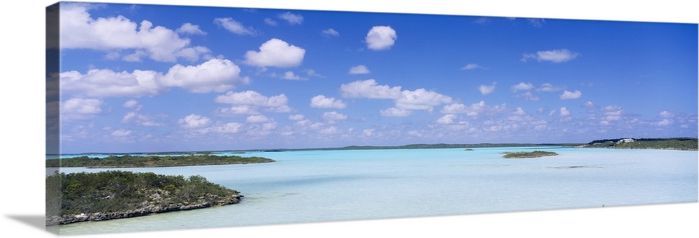 Panoramic photograph of inlet with grass covered sand bars under cloudy skies.