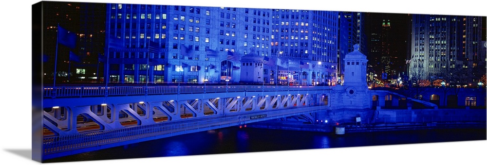 Panoramic view of the Michigan Avenue Bridge during the night. The buildings in the background and the bridge are lit up.