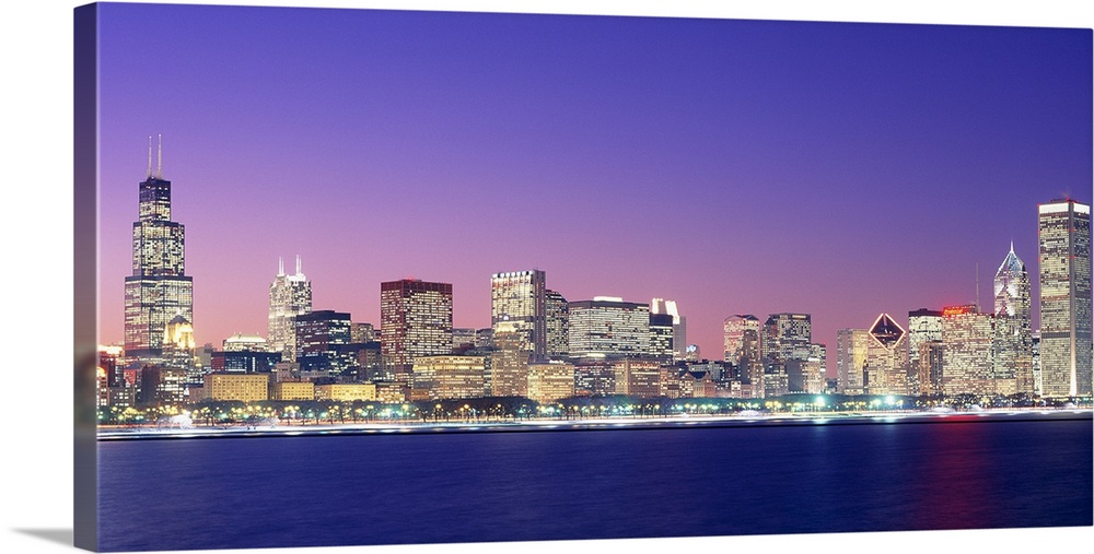 Large photo on canvas of a lit up cityscape by the waterfront at dusk.