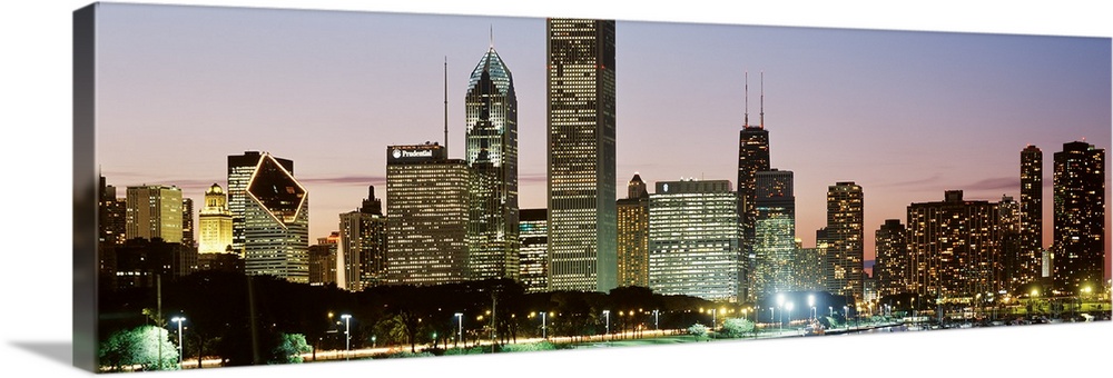 Panoramic print of a cityscape illuminated at dusk along a waterfront.
