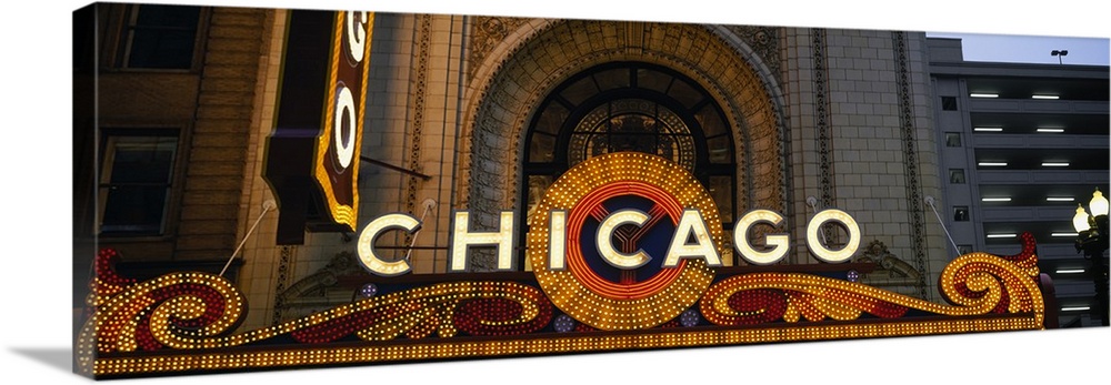 Panoramic photograph focuses on the intricately lit marquee that sits above the entrance of an auditorium within the large...