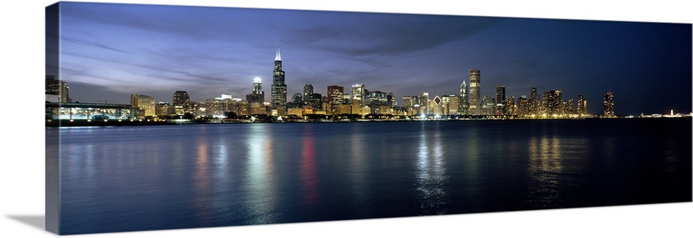 The entirety of the cityos sky rises fill the landscape and reflect in the lake water of this panoramic photograph.